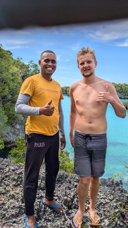Two men giving a thumbs-up beside a lagoon in the Kei Islands